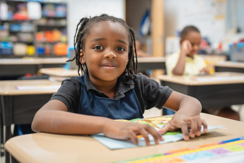 The importance of school attendance. Northwestern Legends Elementary student smiling at desk with a book