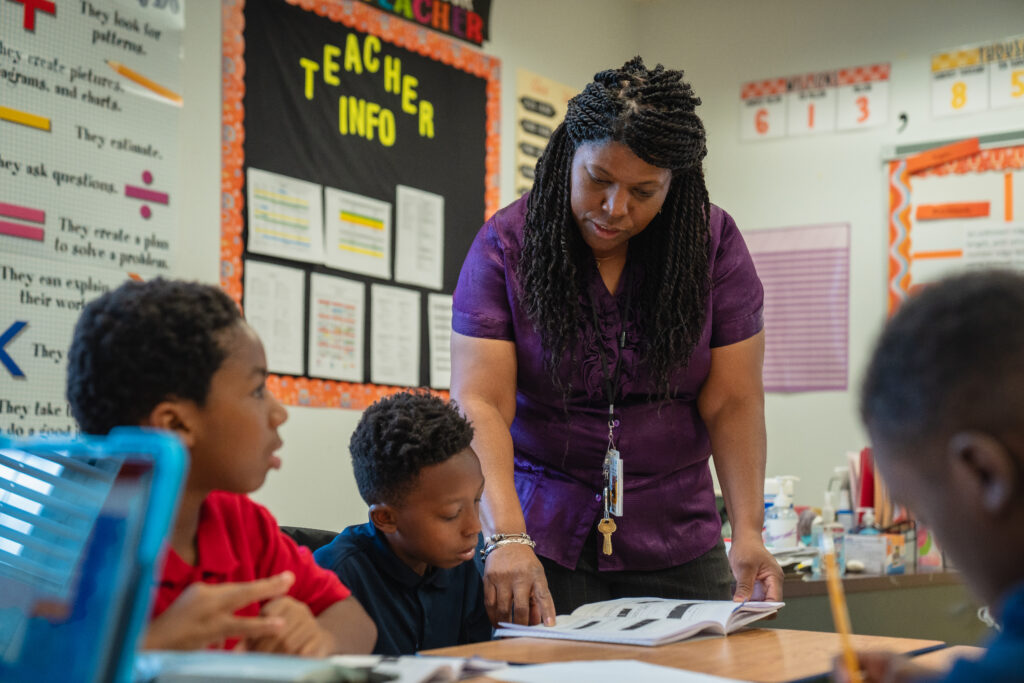 Teacher at Northwestern Legends Elementary School helps a group of students in a workbool