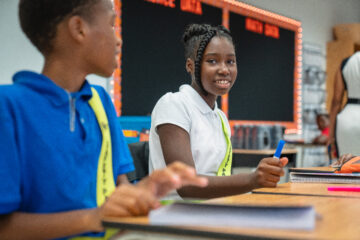 Why is school attendance important? Young girl at Northwestern Legends Elementary sitting at desk smiling